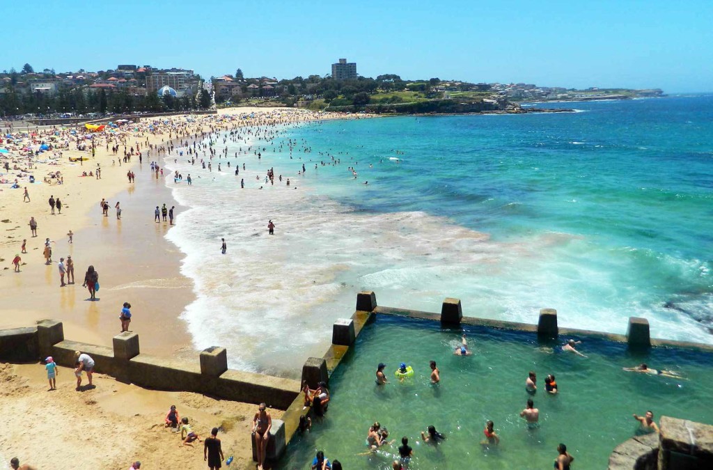 Banhistas lotam a piscina de pedra de Coogee, em Sydney, com a praia do mesmo nome ao fundo