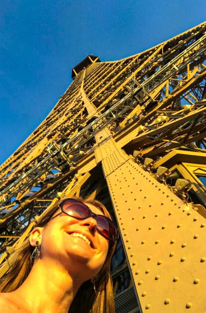 Mulher posa para foto com o topo da Torre Eiffel acima dela