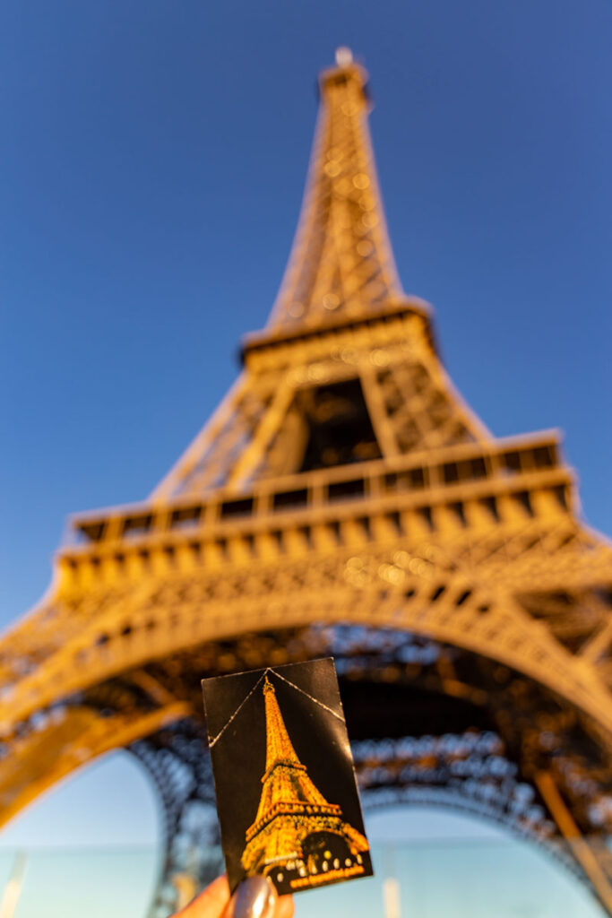 Mão segura ingresso com a Torre Eiffel ao fundo