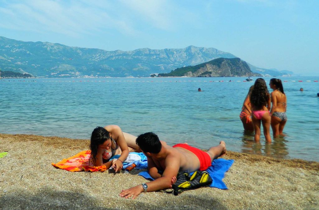 Jovens conversam e tomam banho de mar em praia de Montenegro