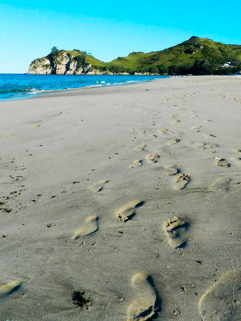 Passos na areia da praia de Hahei, na Nova Zelândia
